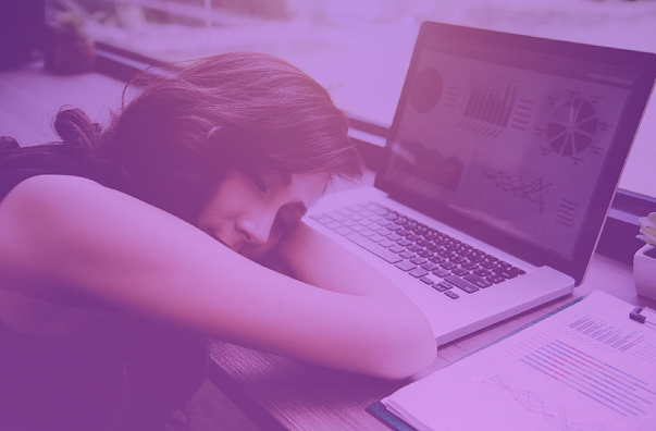 Mujer durmiendo sobre su escritorio junto a una laptop con gráficos financieros complejos y reportes impresos. La imagen, con un filtro morado, representa el agotamiento administrativo y la ineficiencia de usar Excel para la contabilidad de propiedad horizontal frente a la automatización de software especializado.